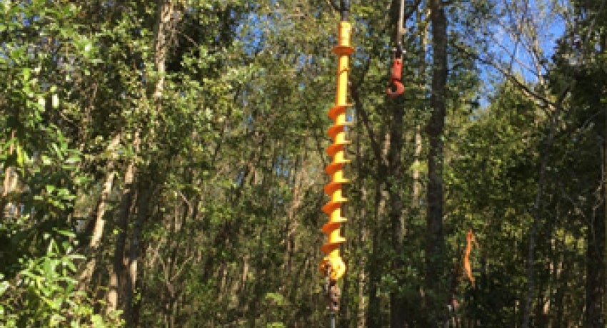 In the woods of Colleton County, lineworkers position the auger of a flexible-track mounted vehicle to drill a power pole hole on Oct. 11. 